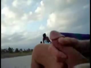 Americký turistický škubání na the pláž zatímco žena passing podle video